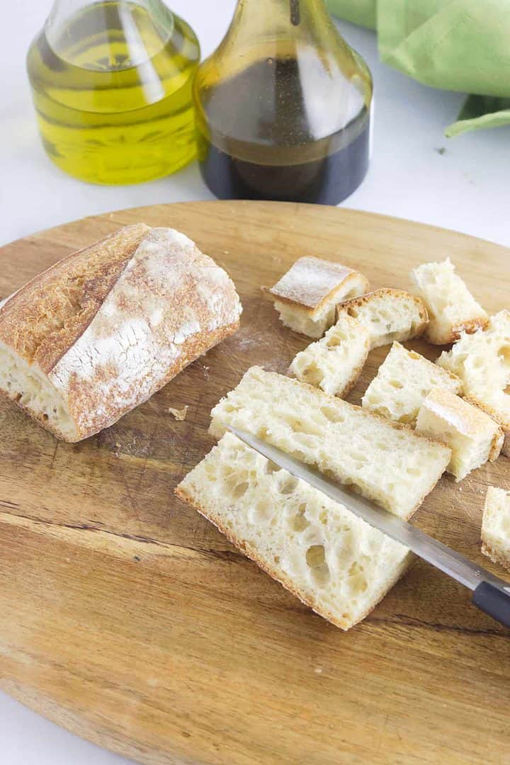 baguette bread cubed on a cutting board.