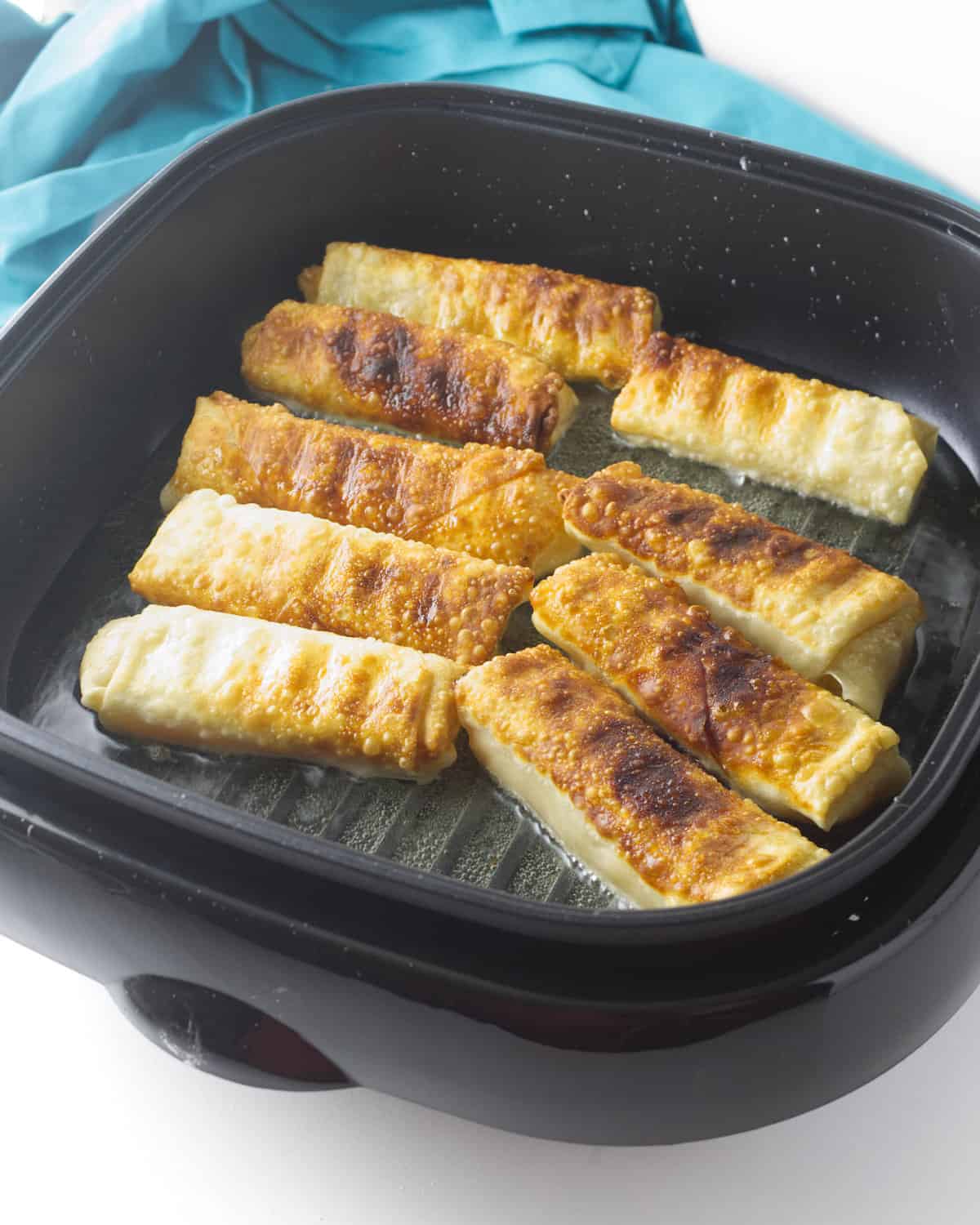 chicken fry pan with egg rolls browning.