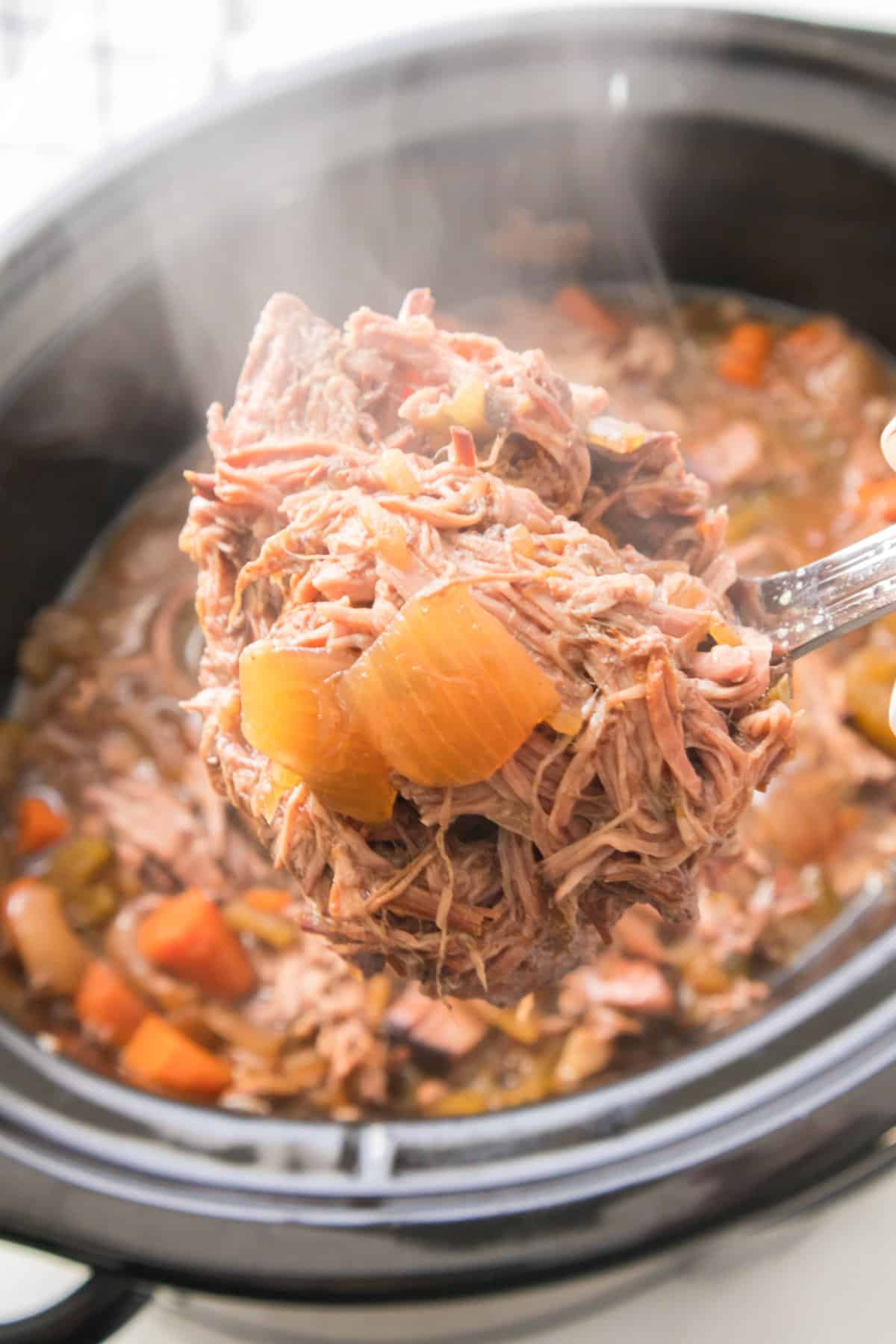 Slow cooker with ready to serve pot roast stew and carrots.