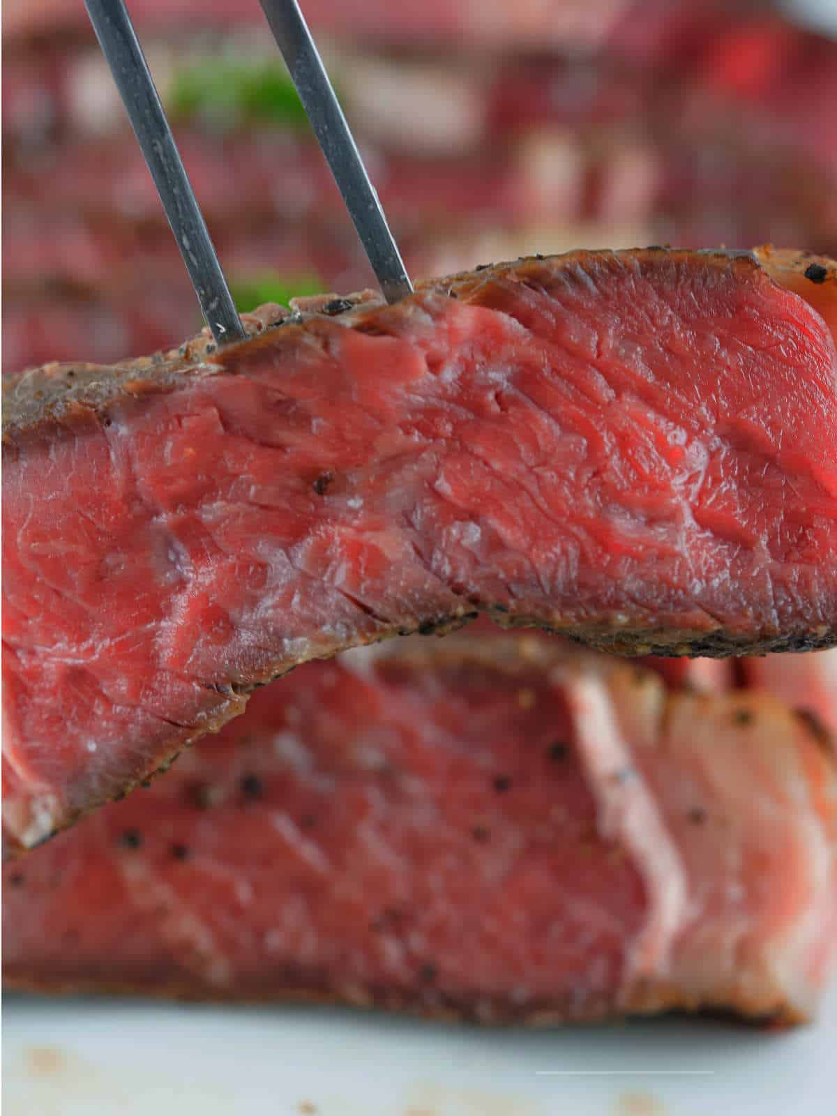 a fork holding a slice of sous vide ribeye steak.
