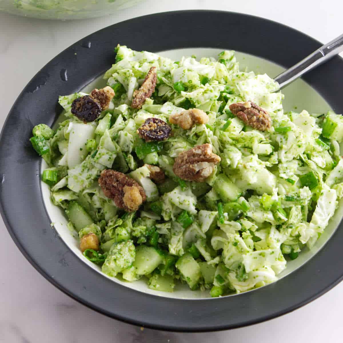 tiktok green goddess salad in a bowl with candied almond garnish.