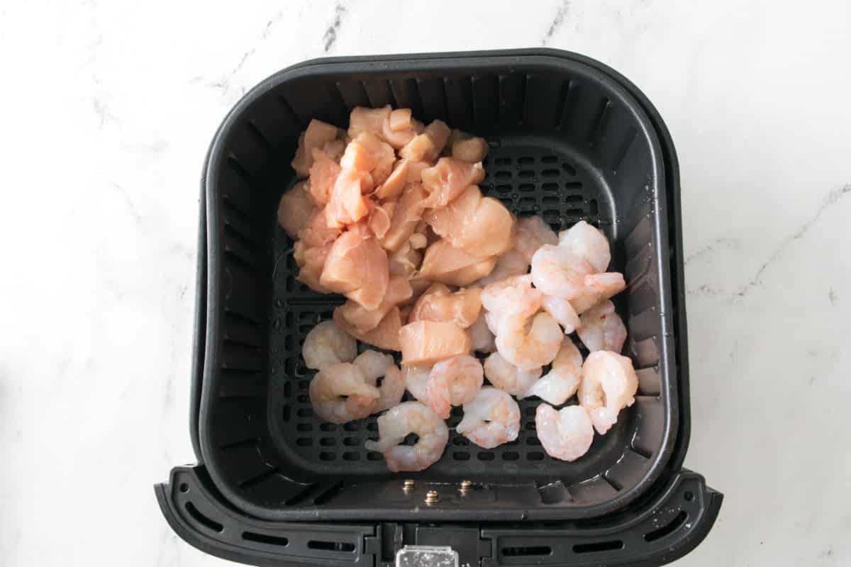 raw chicken and raw shrimp in an air fryer.
