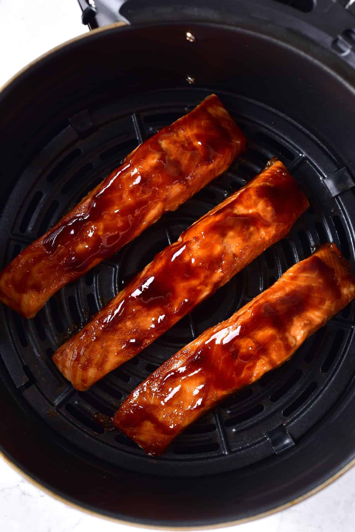 teriyaki glazed salmon steaks cooking in an air fryer.