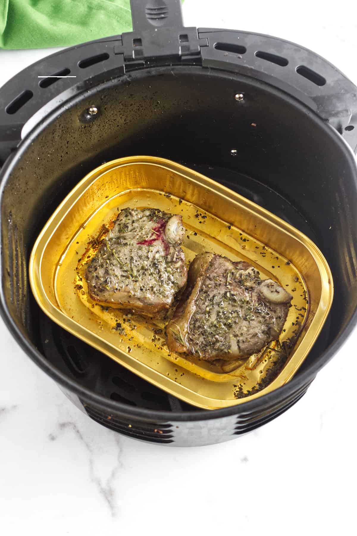 two small steaks cooking in an air fryer.