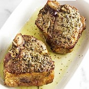 two air fried lamp chops in a serving bowl with compound butter nearby.