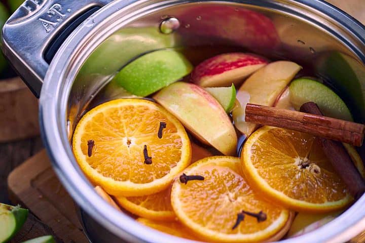 apples and oranges with spices in a simmer pot.