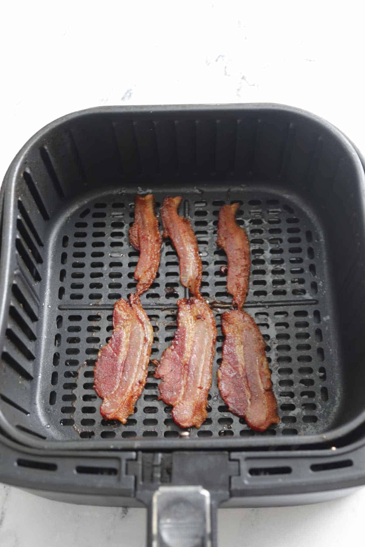 bacon in an air fryer basket.