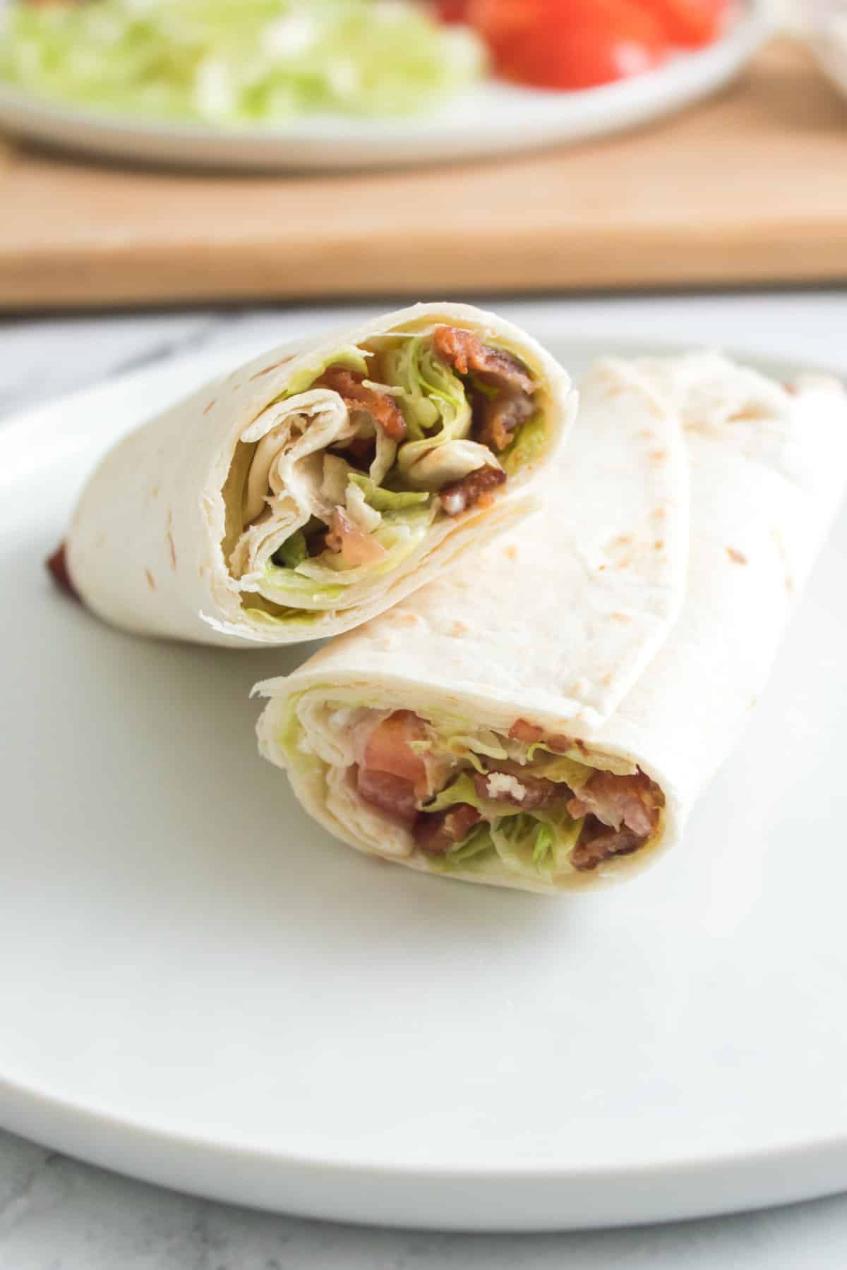 rolled up wrap on a plate and sliced in half.