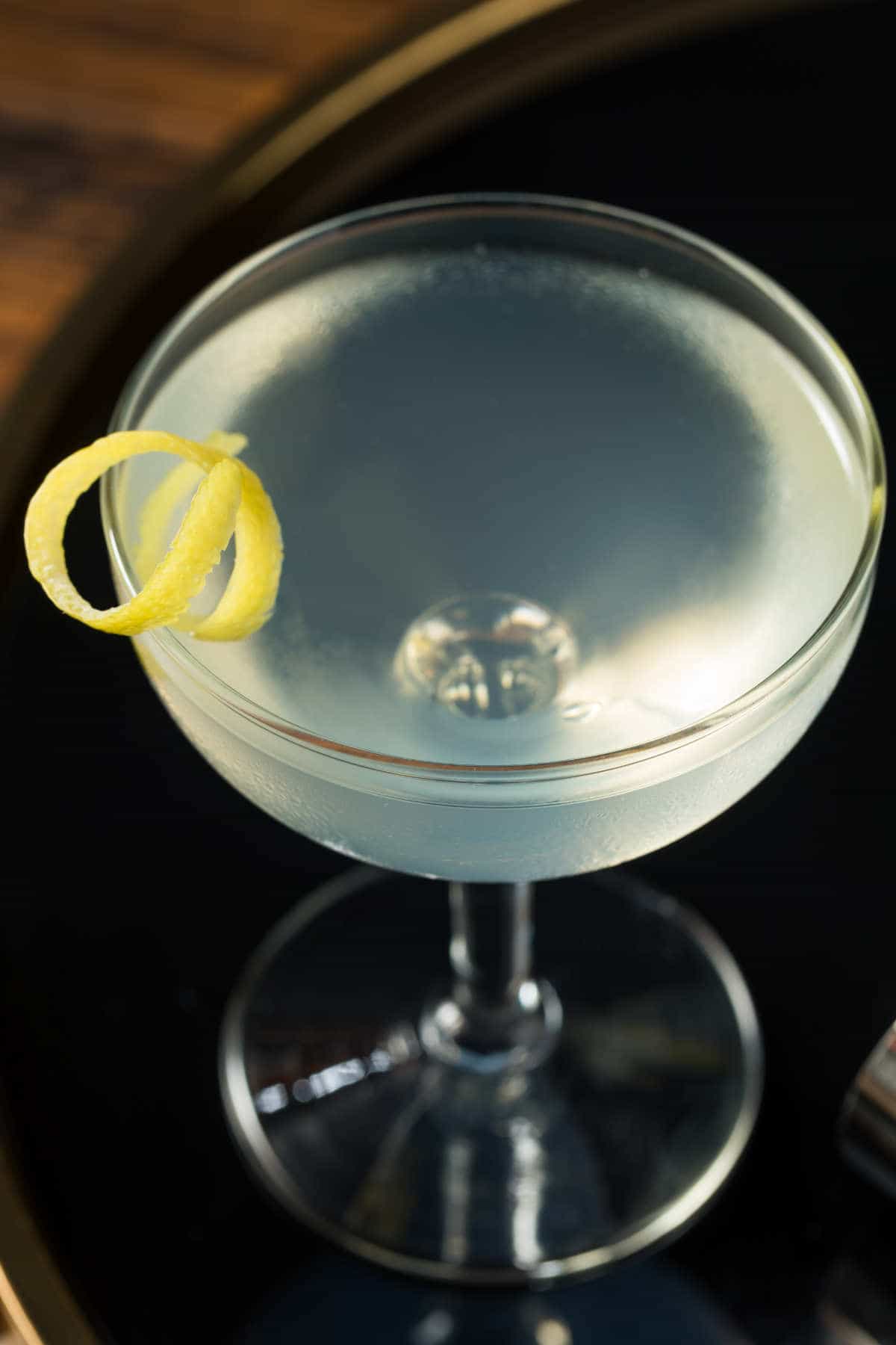 Casino Royale Vesper Martini with a twist of lemon on a black serving tray.