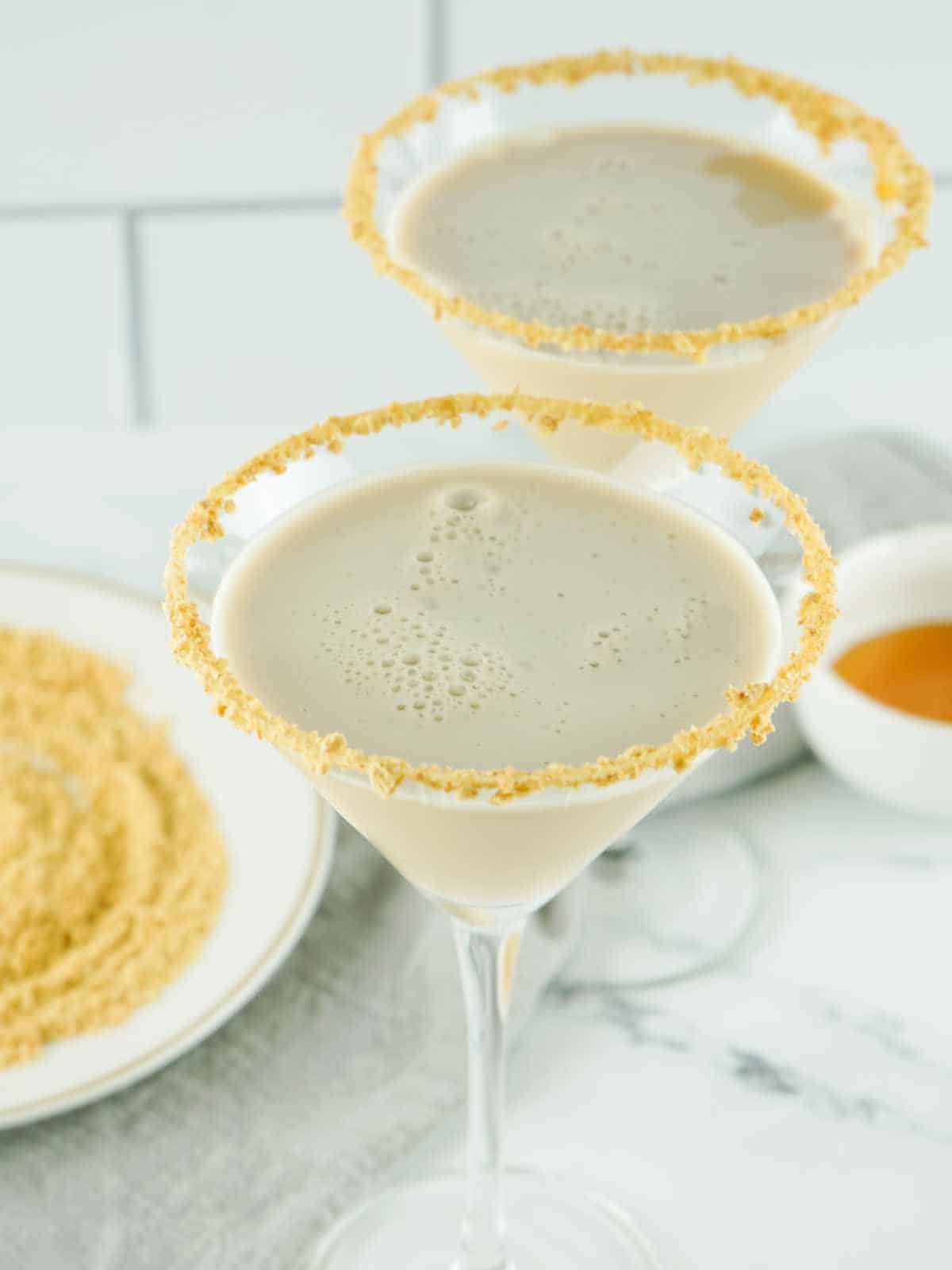 two cheesecake cocktails with graham cracker rims.