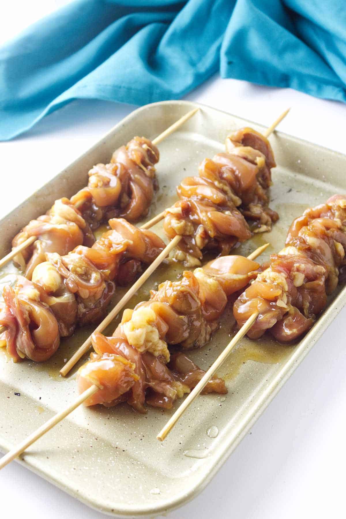 raw marinated chicken pieces on sticks ready for grilling or oven baking.