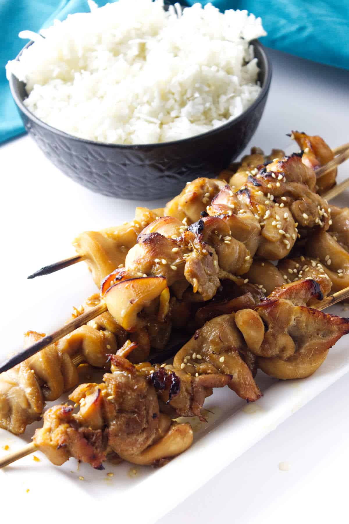 Platter of teriyaki chicken skewers and a bowl of white steamed rice.
