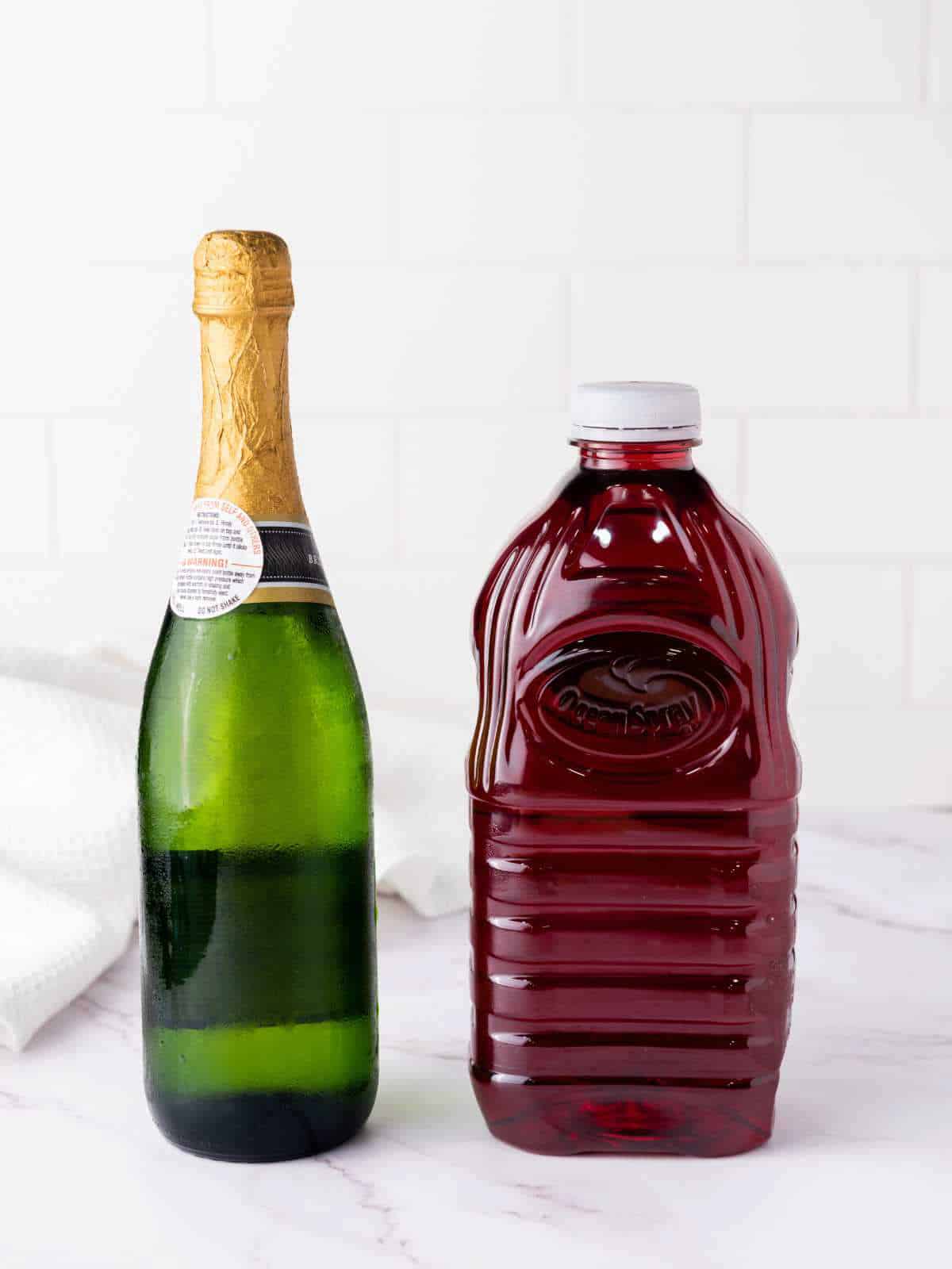 bottle of sparkling wine and a bottle of cranberry juice.