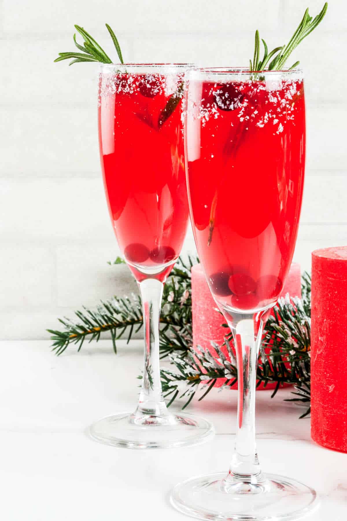 juice and sparkling wine, garnished with a rosemary sprig and cranberries.