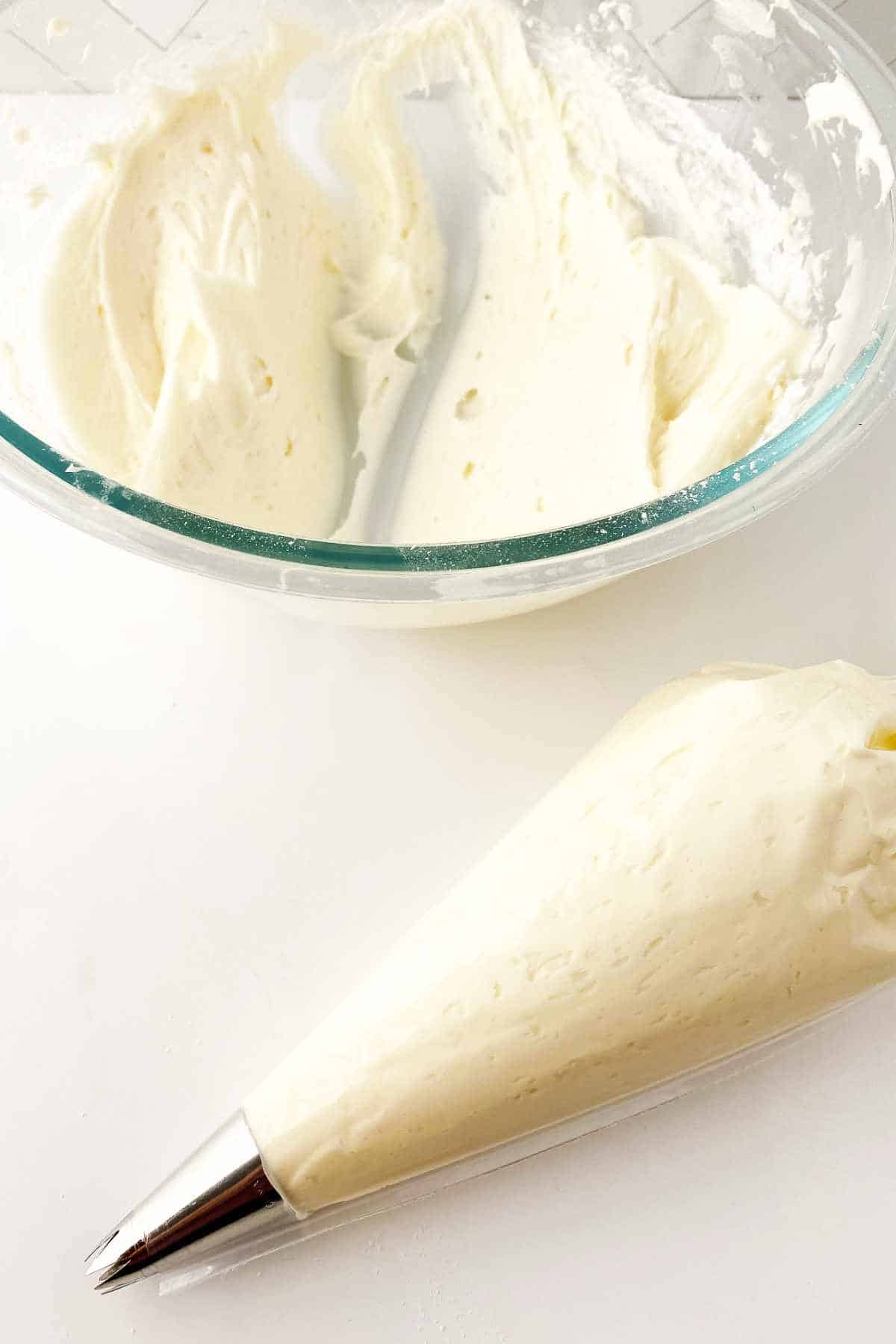 Bowl and piping bag of creamy white icing.