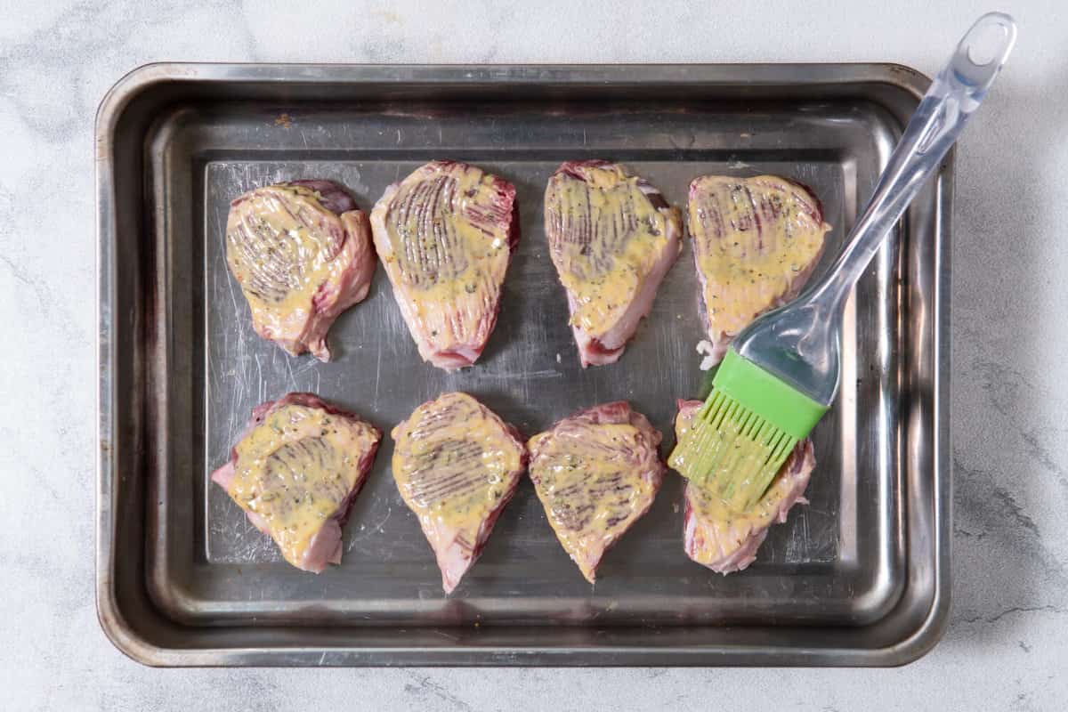 mustard and herb mixture brushed on uncooked lamb chops.