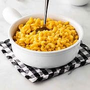 A dish filled with homemade macaroni and cheese with a spoon submerged inside.