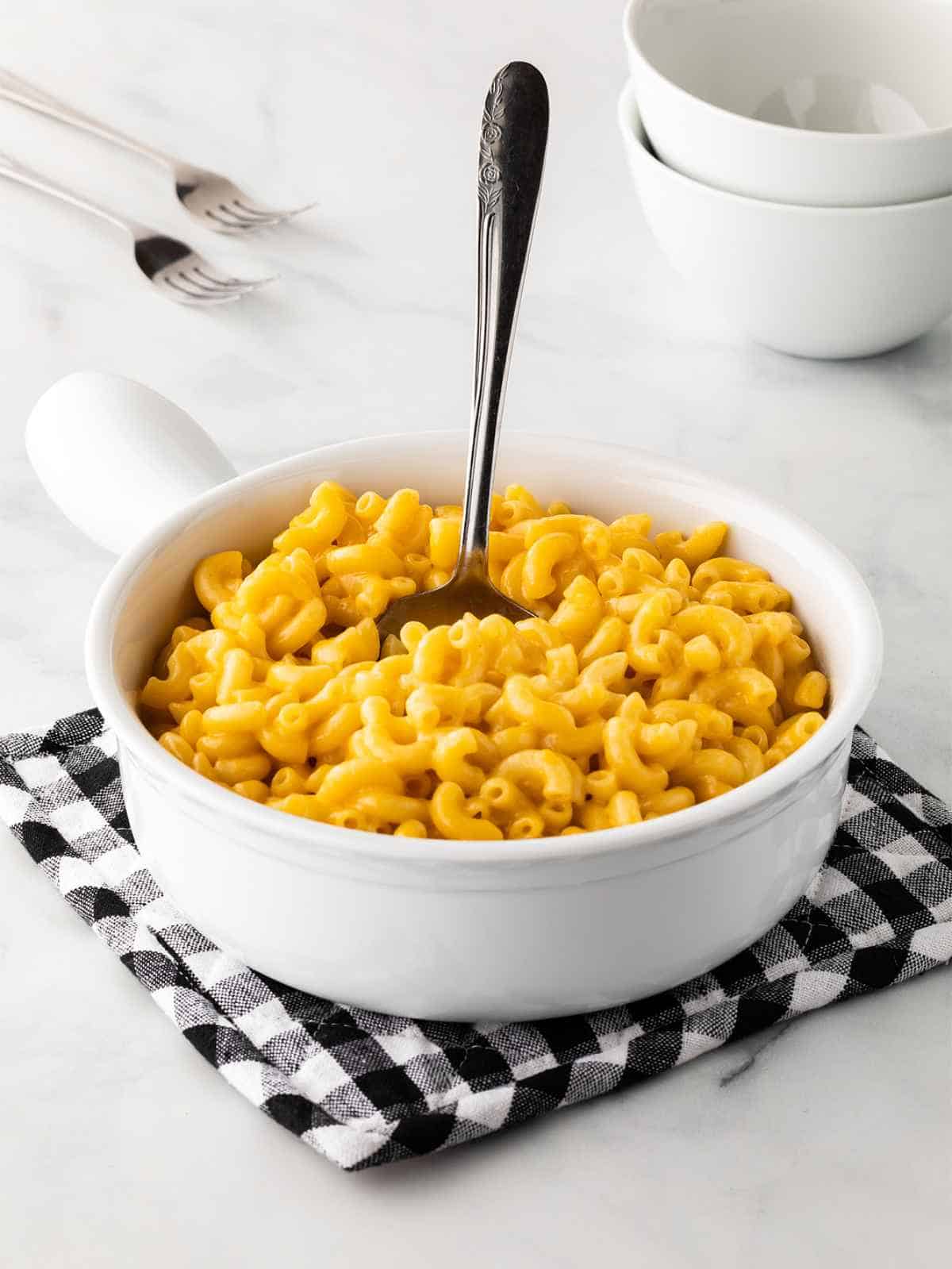 A dish filled with homemade macaroni and cheese with a spoon submerged inside.