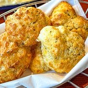 wire basket of cheddar cheese biscuits with butter brushed on top.