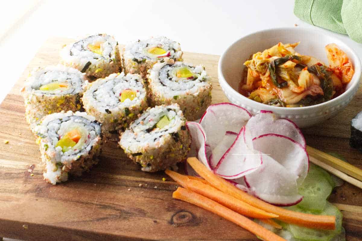 Kimbap Rolls inside out roll on platter with bowl of kimchi.