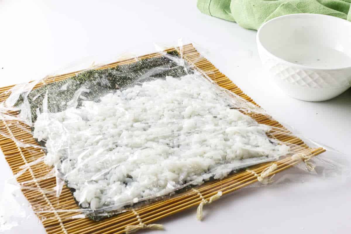 seaweed sheet covered with thin layer of rice and plastic film.