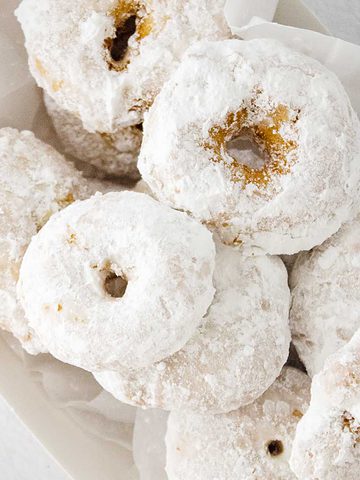 mini powdered sugar donuts in a bowl.