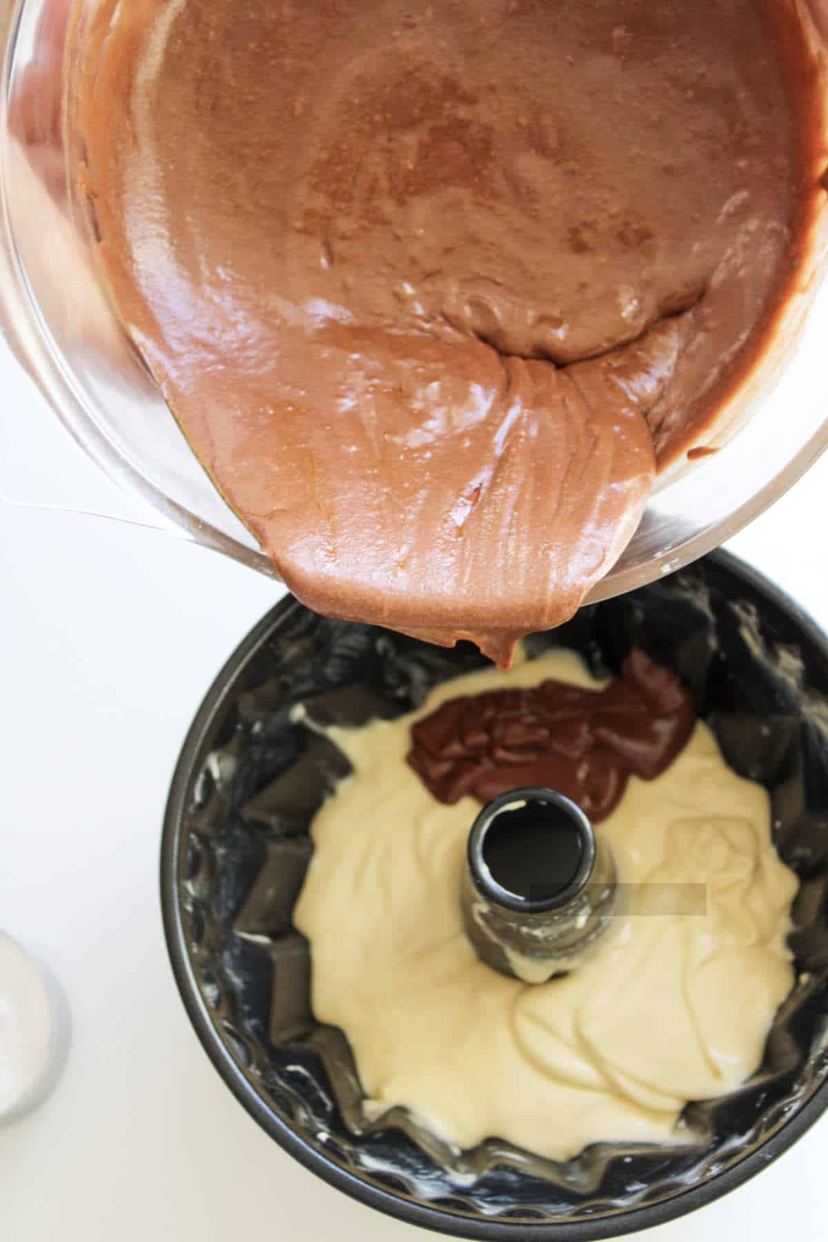 layering vanilla and chocolate cake batter in a bundt pan.
