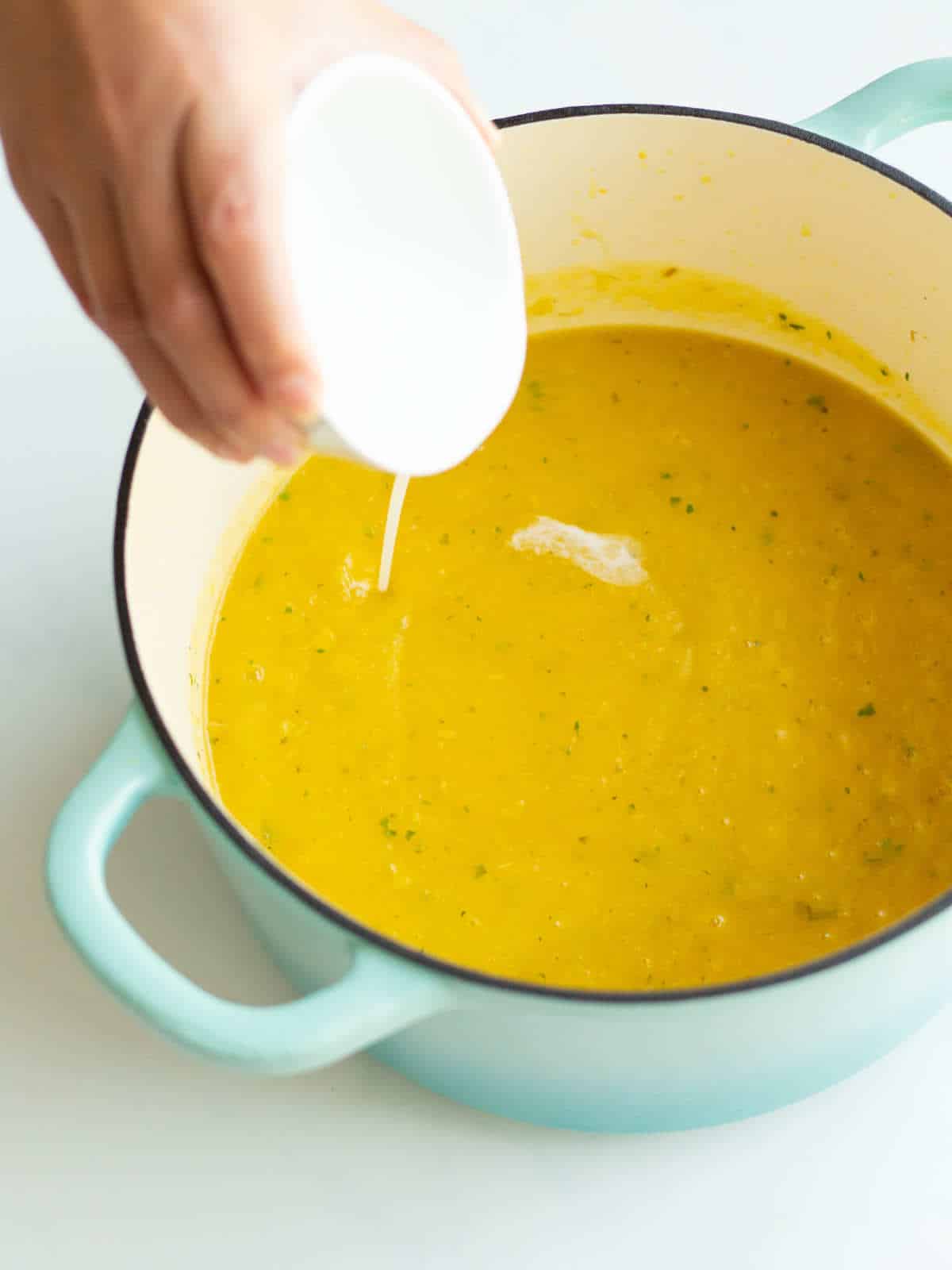 cream added to soup pot of creamy butternut squash soup.