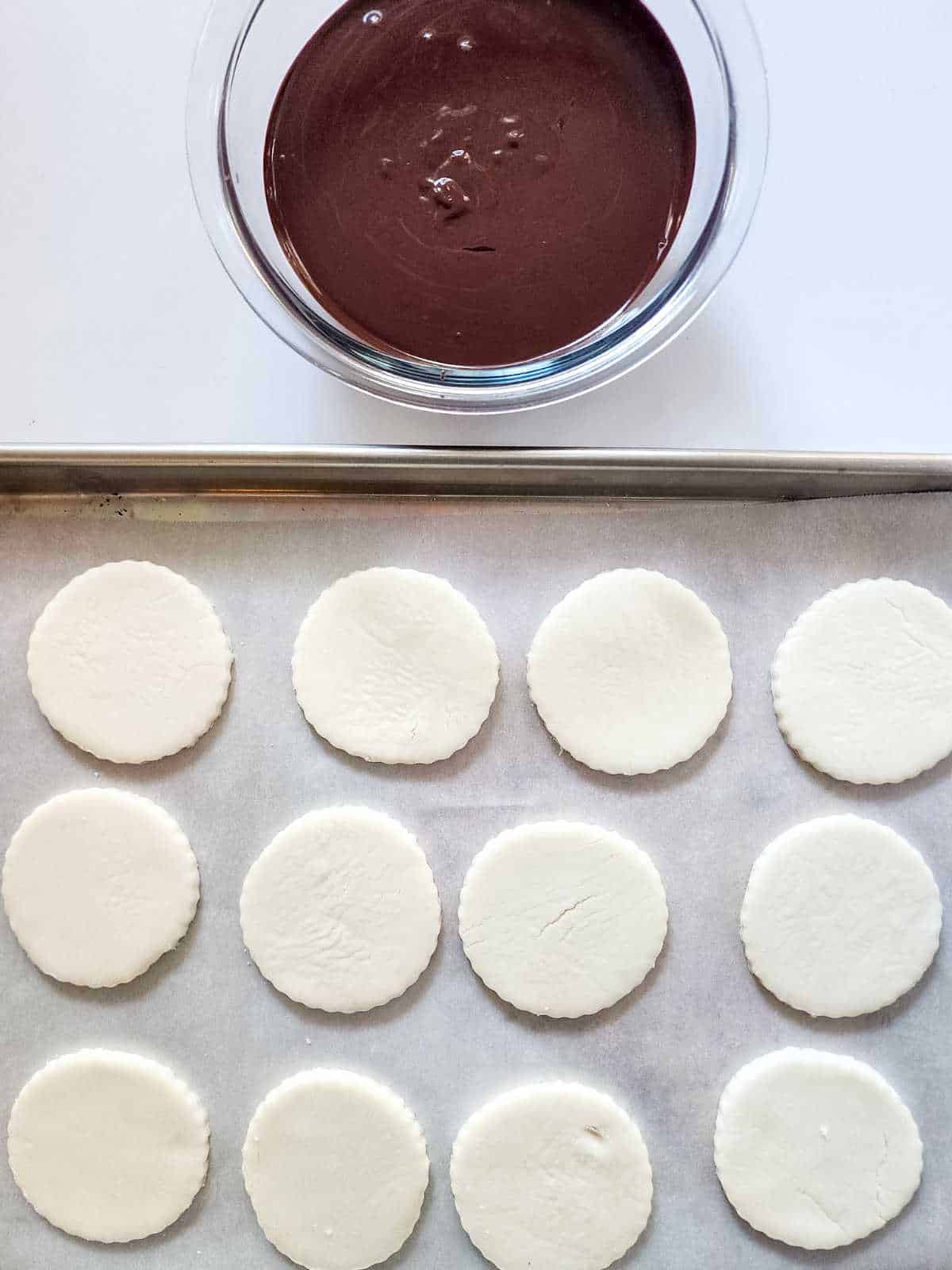 chilled candy dough circles with melted chocolate nearby.