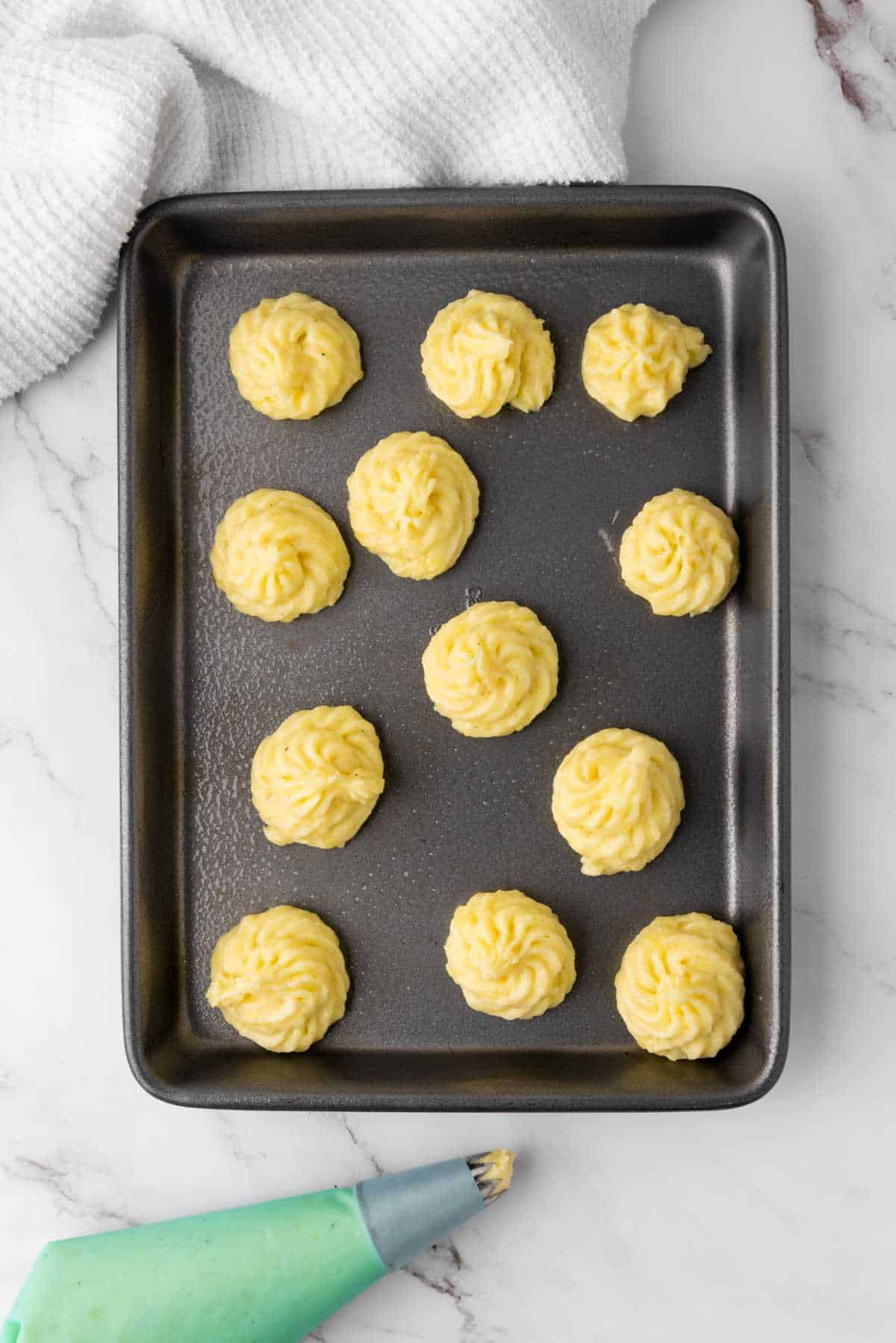 piped potato puffs on a tray for baking.