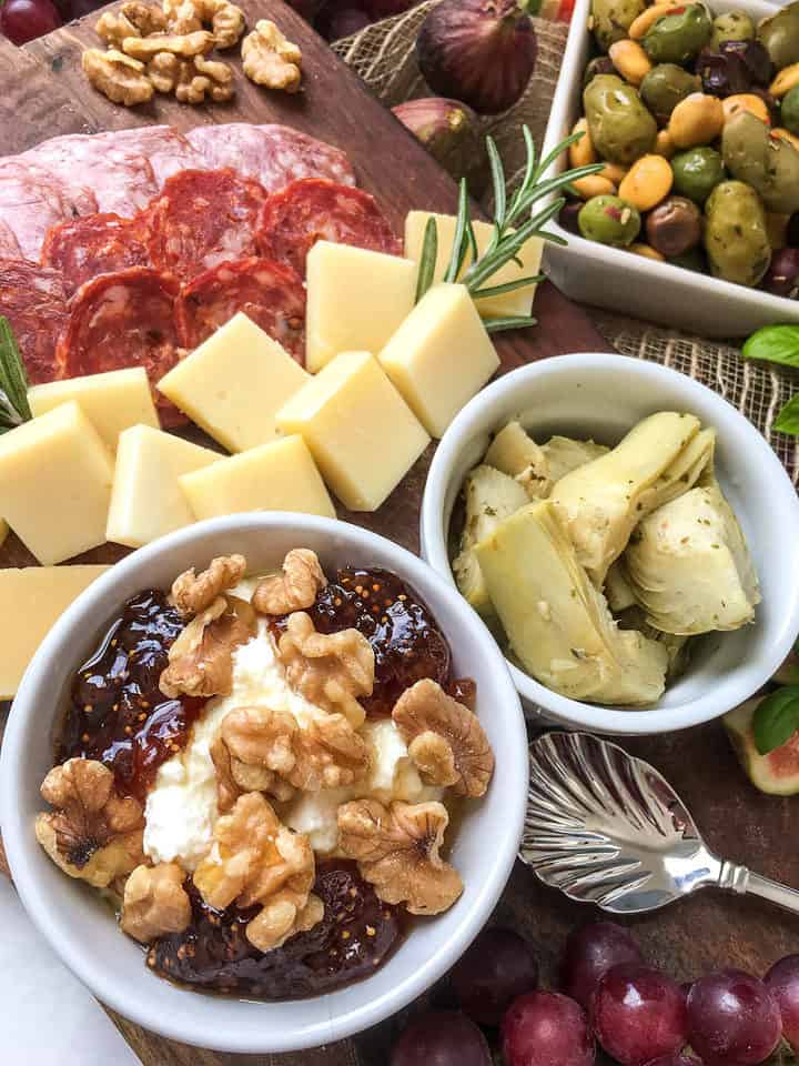 cut cheeses, cut curred meats, and vegetables for an Italian charcuterie platter.