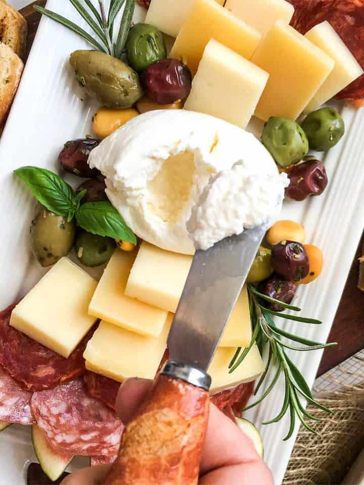 Serving platter with Italian charcuterie meat and cheese on a board.