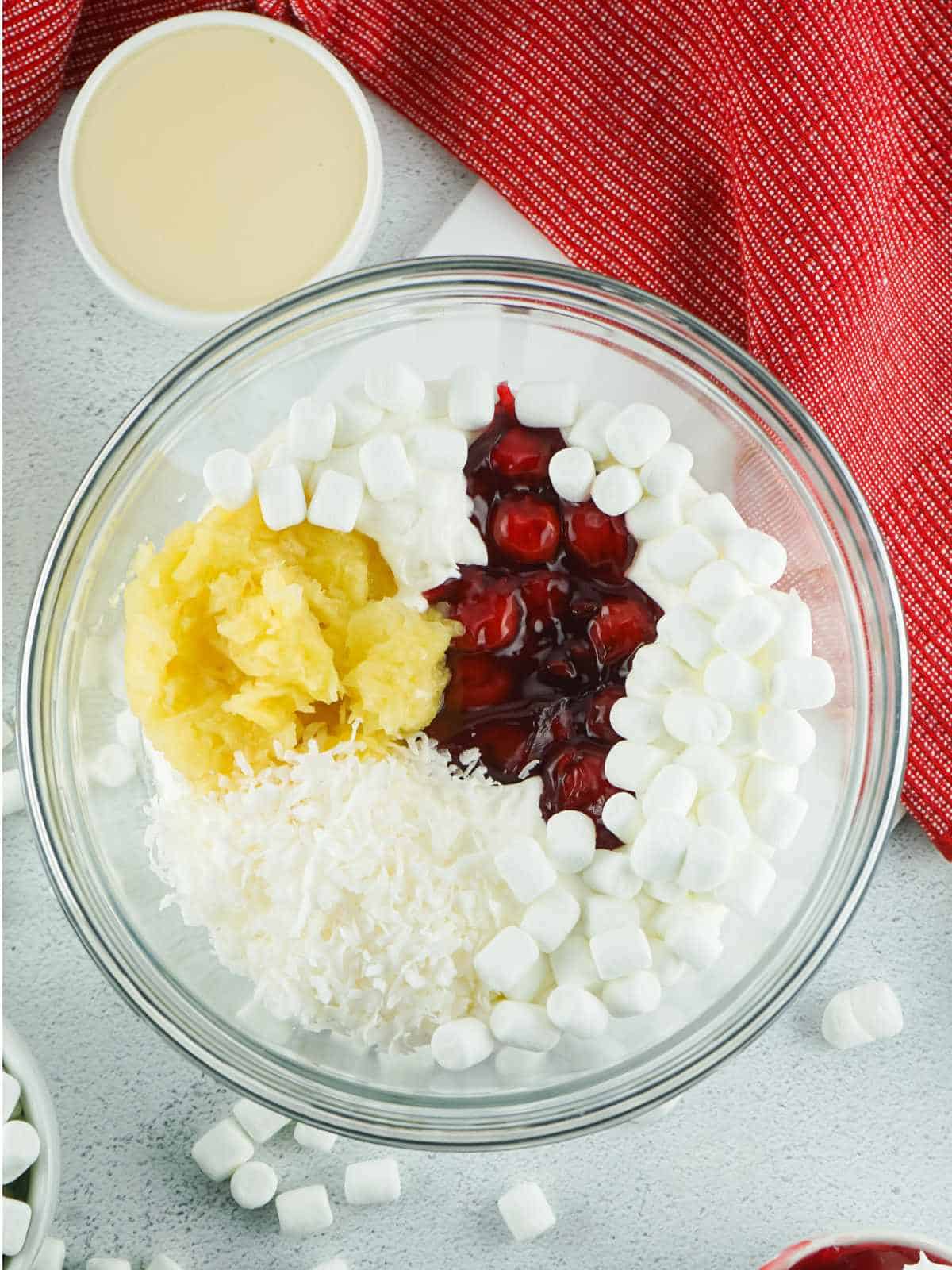 bowl of pineapple, coconut, mini marshmallows, and cherry pie filling.