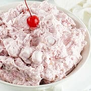 cherry fluff in a bowl, garnished with a maraschino cherry.