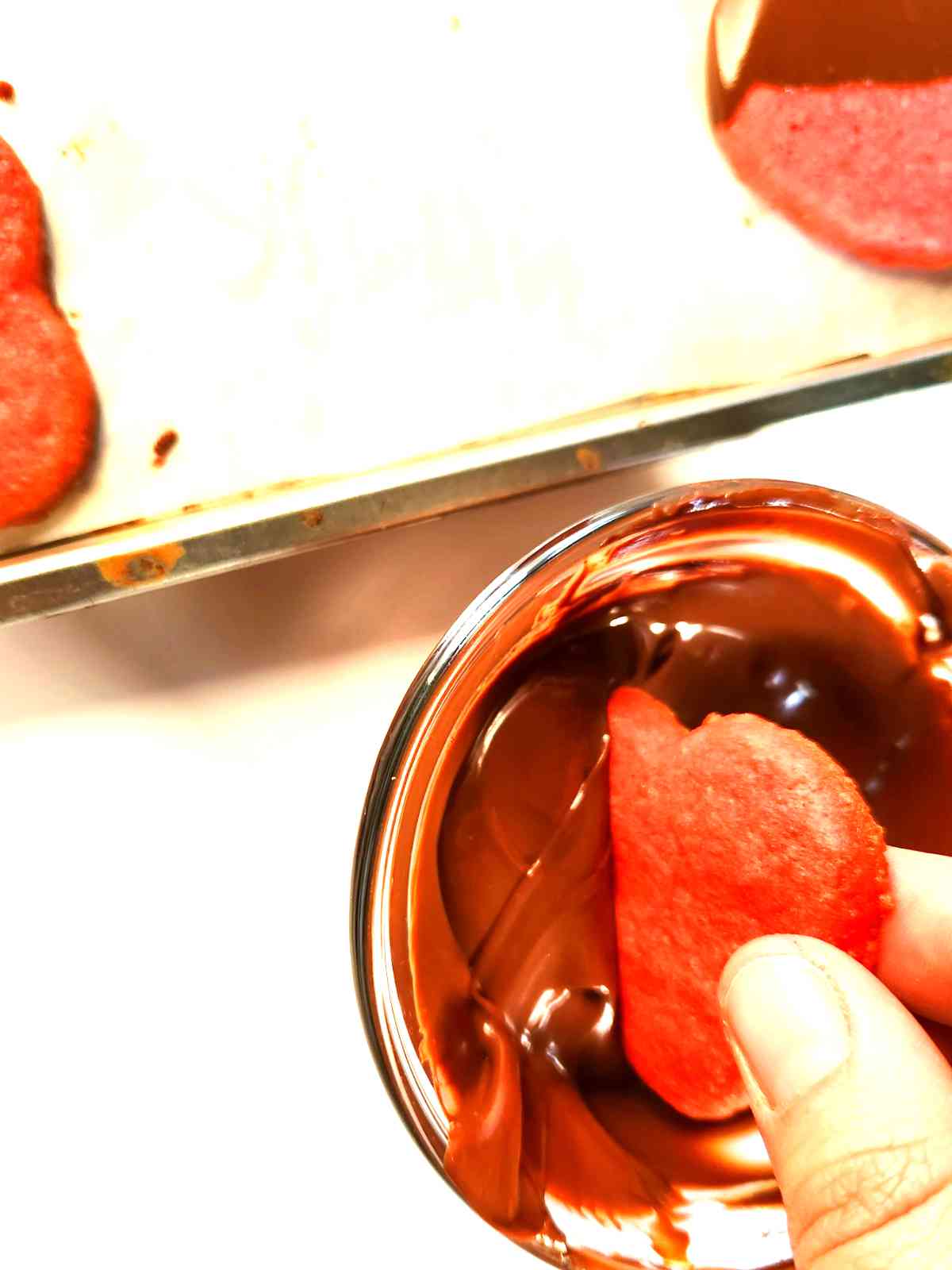Dipping pink heart cookies in melted chocolate.