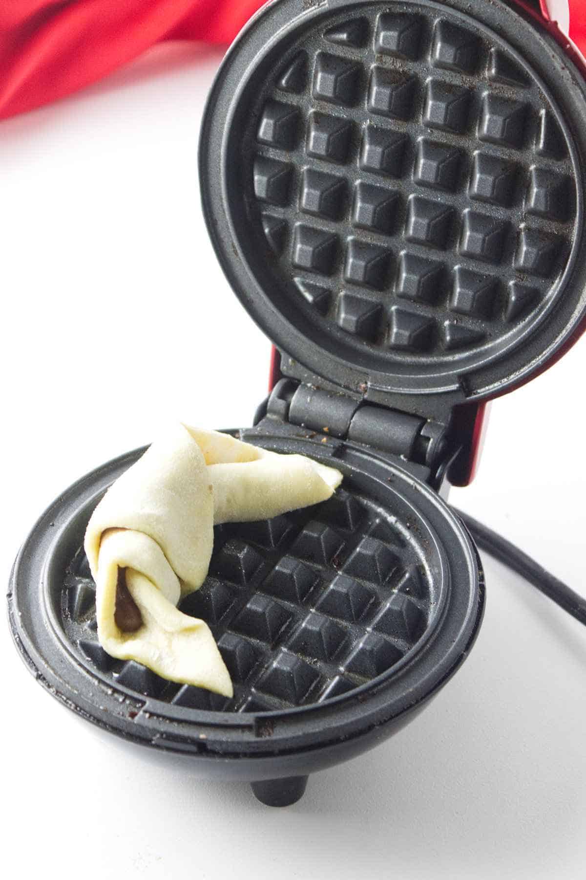 rolled puff pastry crescent set inside a waffle iron.