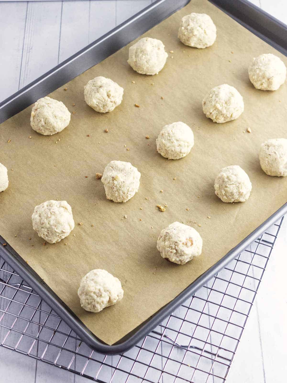 baked snowball cookies on a cookie sheet, ready to be rolled in powdered sugar.
