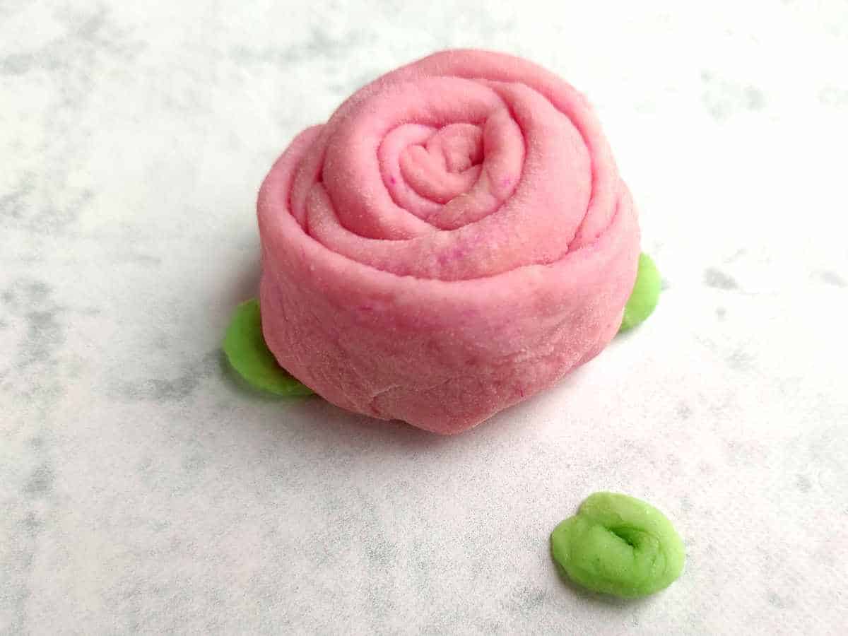 pink tinted dough shaped like a rose bud mantou bun.