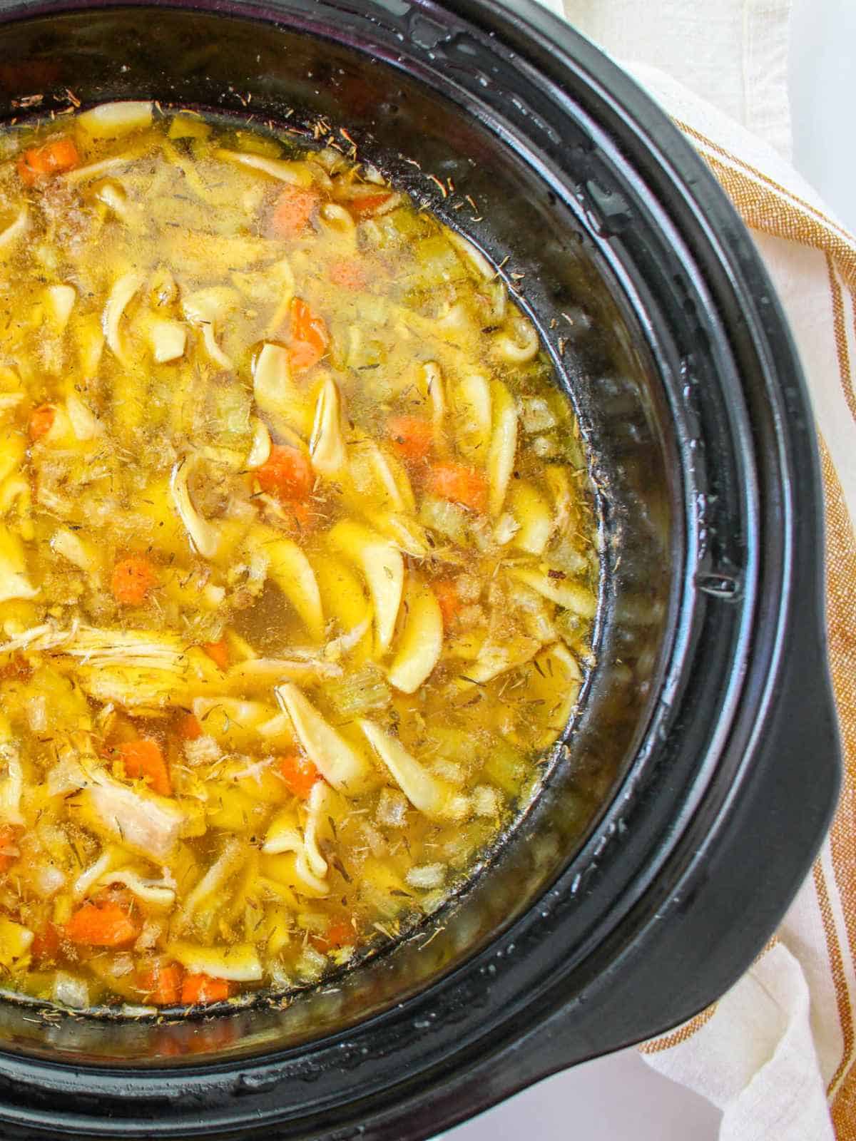 carrots, celery, onion, chicken broth, chicken, and noodles added to a crockpot.