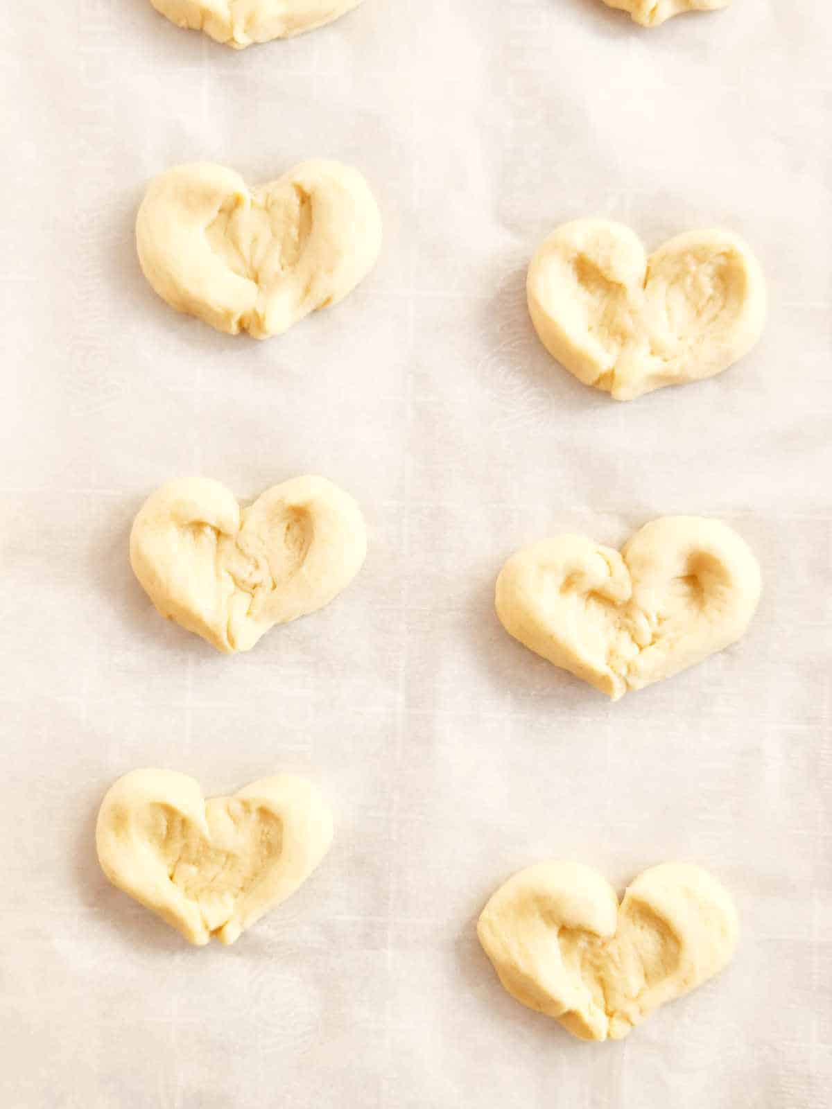 breakfast cheese danish shaped like hearts on a baking pan.