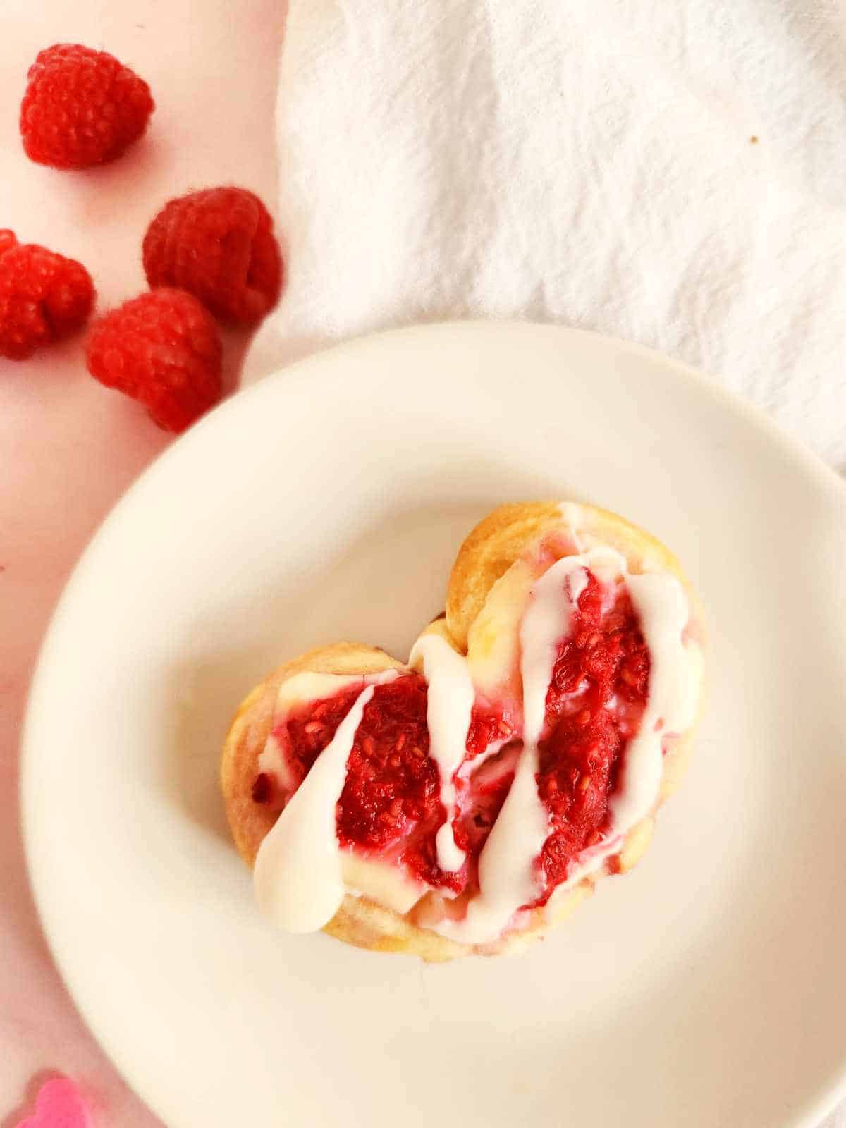 crescent roll cheese & raspberry danish with icing drizzled on top.
