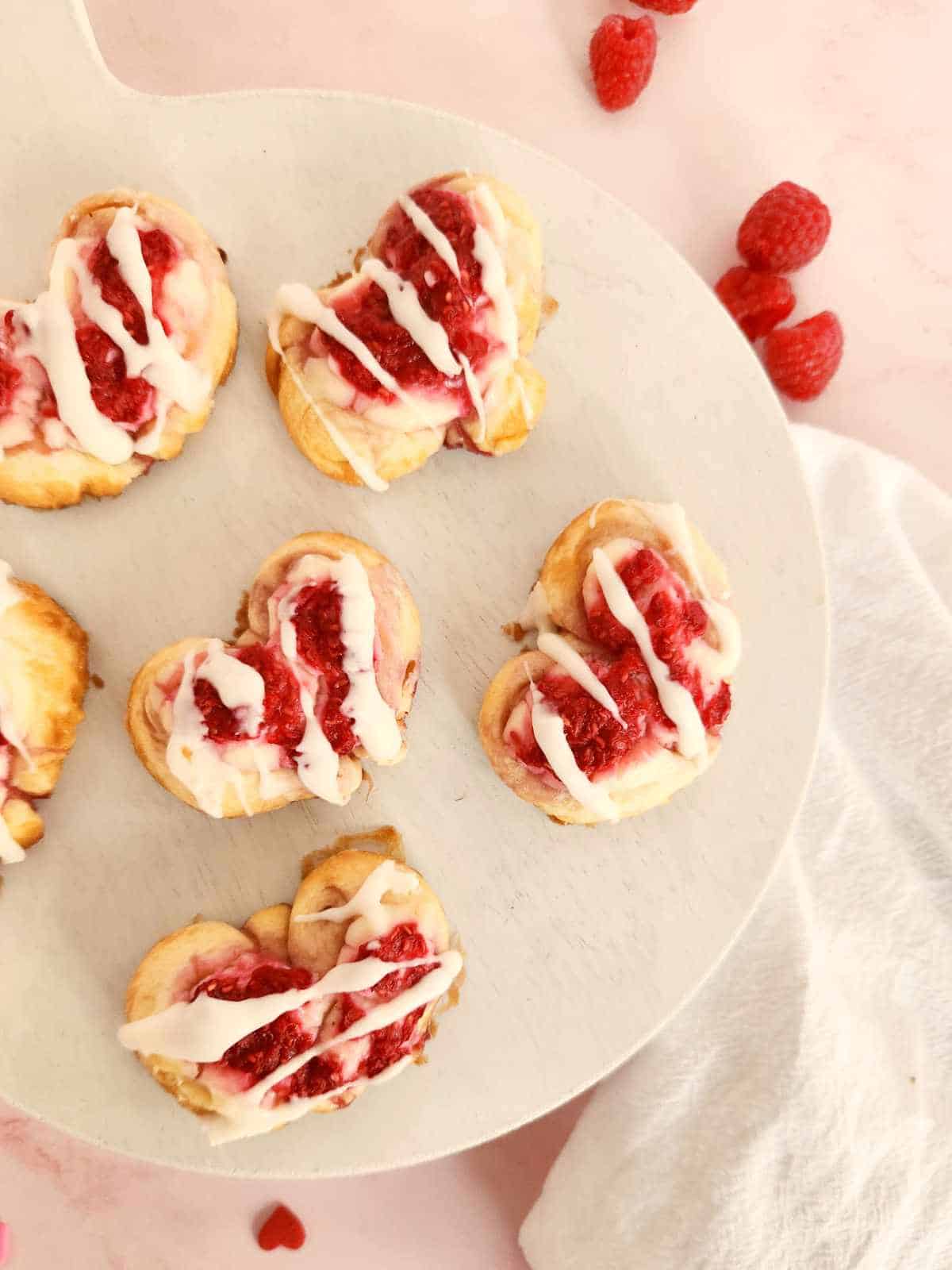 raspberry cream cheese hearts on a plate with drizzled icing.