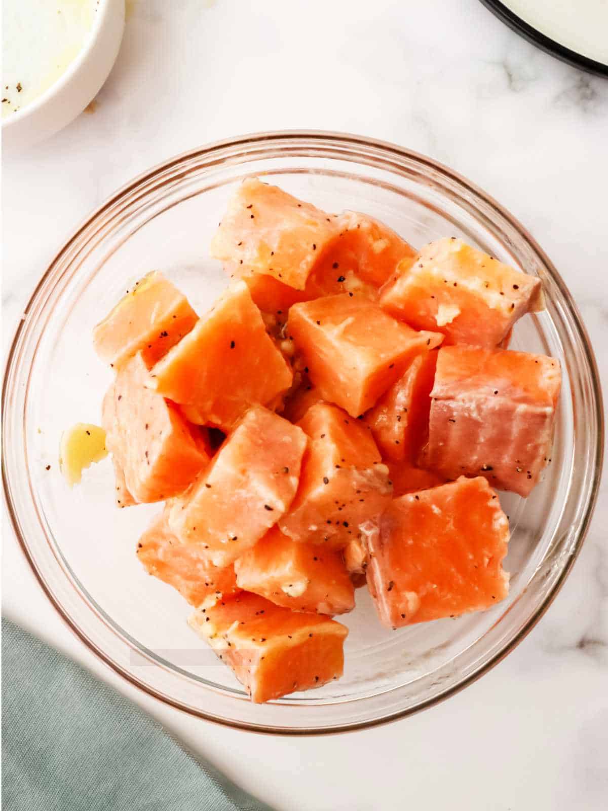 cubes of salmon in a bowl with butter seasoning.