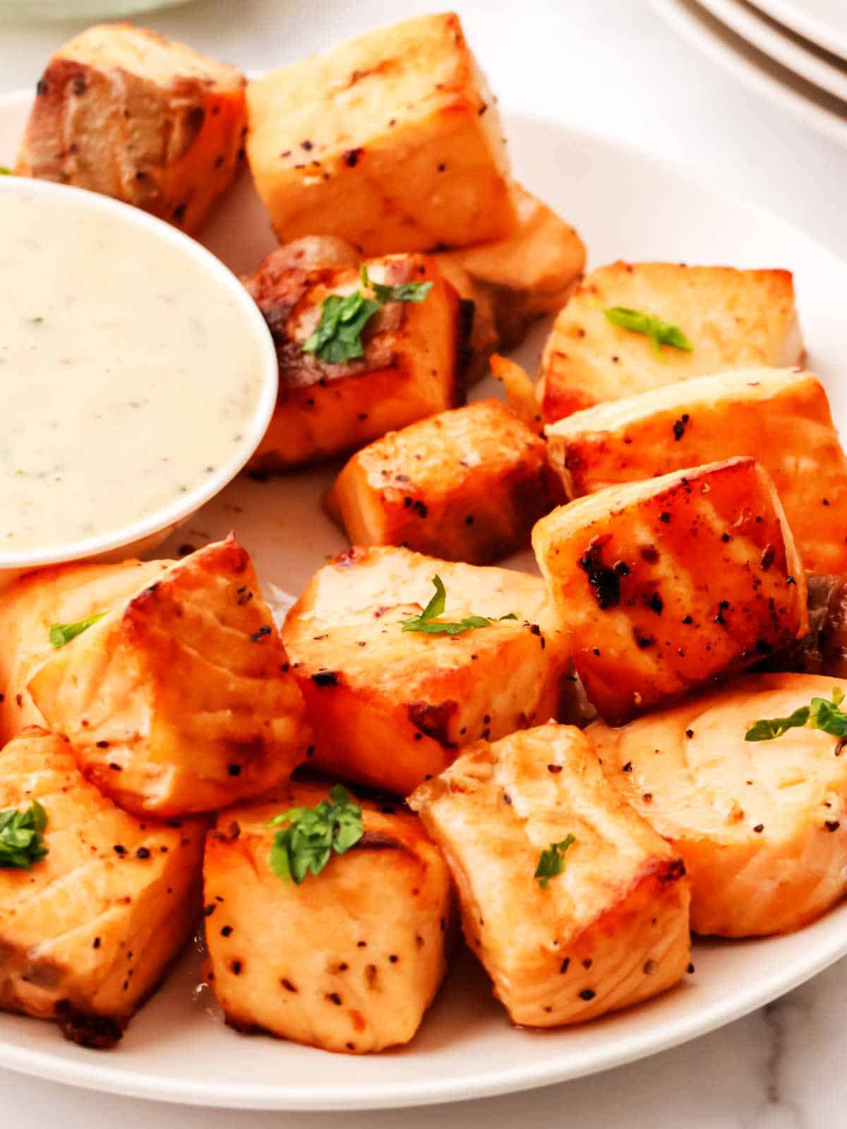 salmon bites on a plate with a dish of tartar sauce.