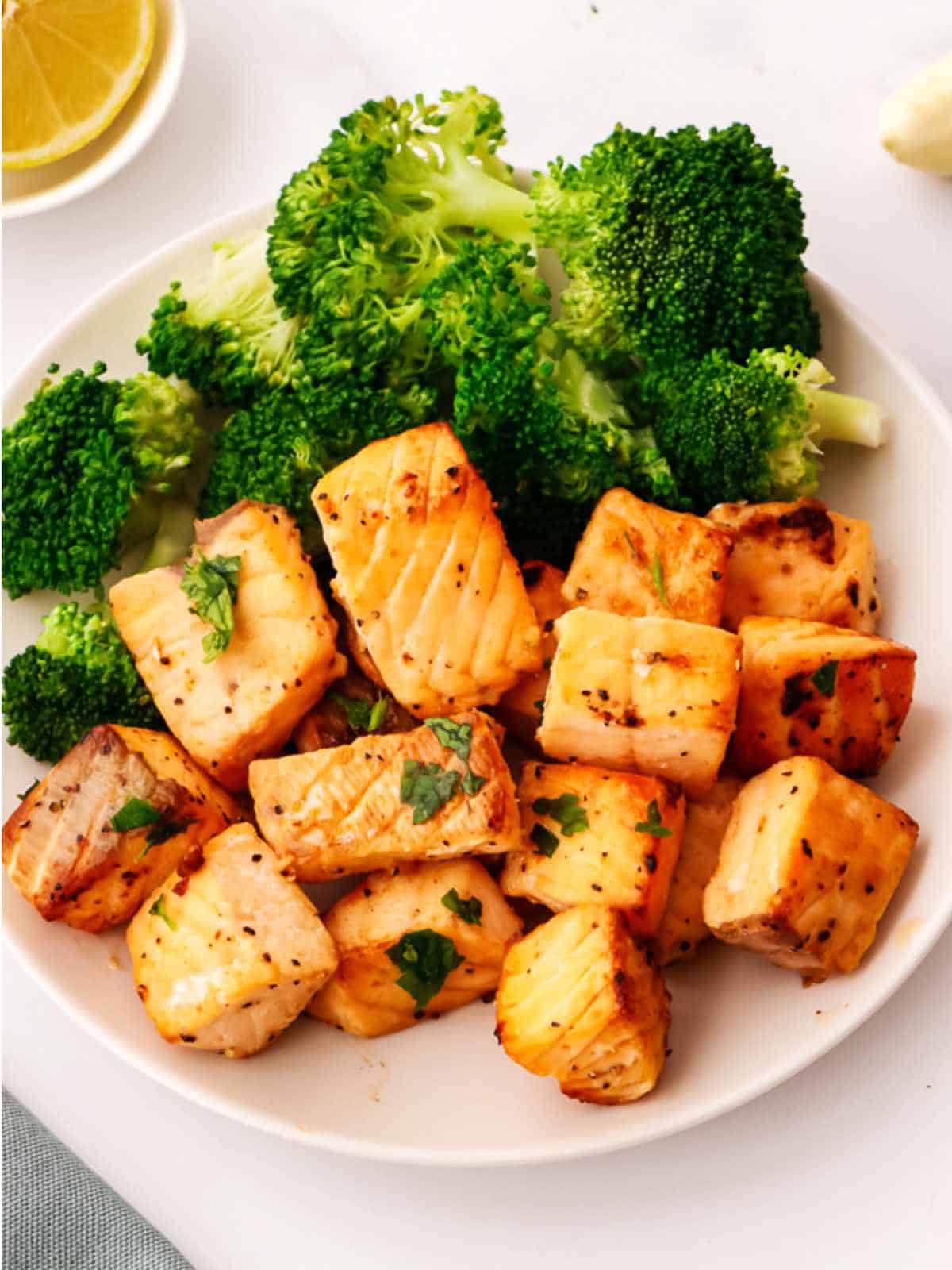 salmon bites on a plate with broccoli.