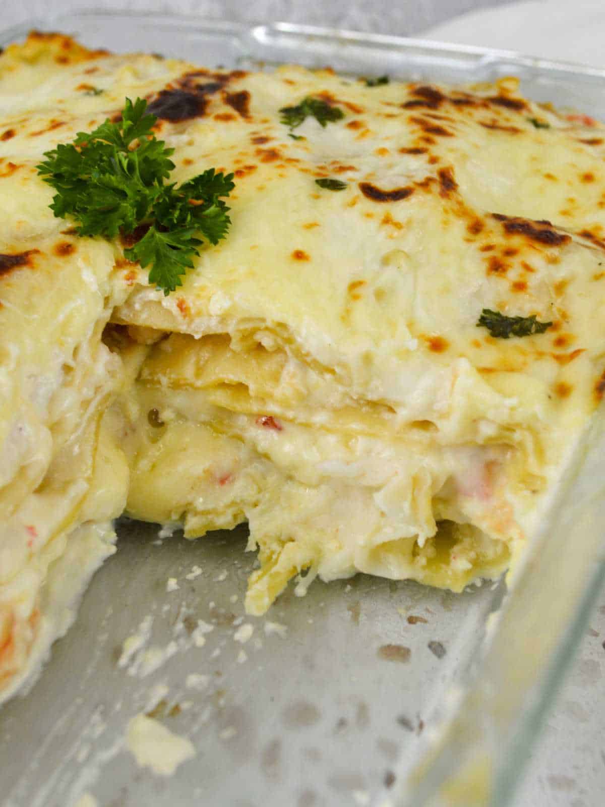 .casserole baking dish of shrimp and crab lasagna with square cut out.