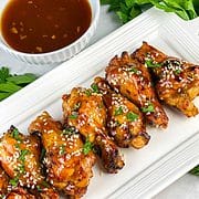 platter of soy ginger chicken wings garnished with sesame seeds and parsley.