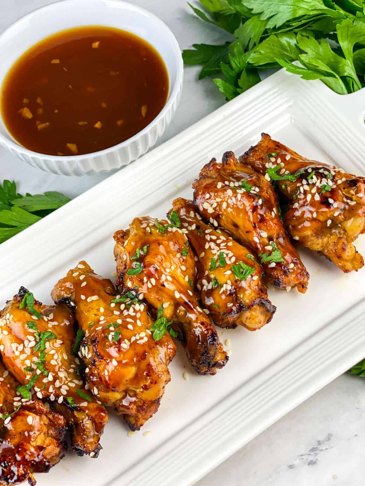 platter of soy garlic chicken wings garnished with sesame seeds and parsley.