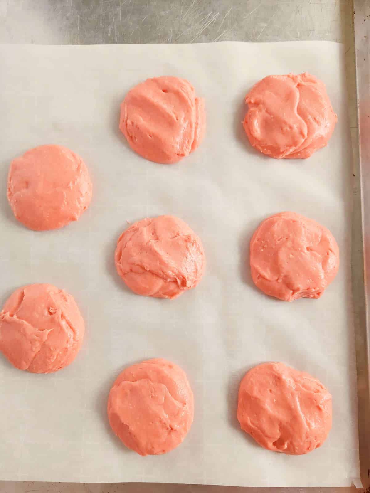 flattened cookies on a parchment covered baking sheet.
