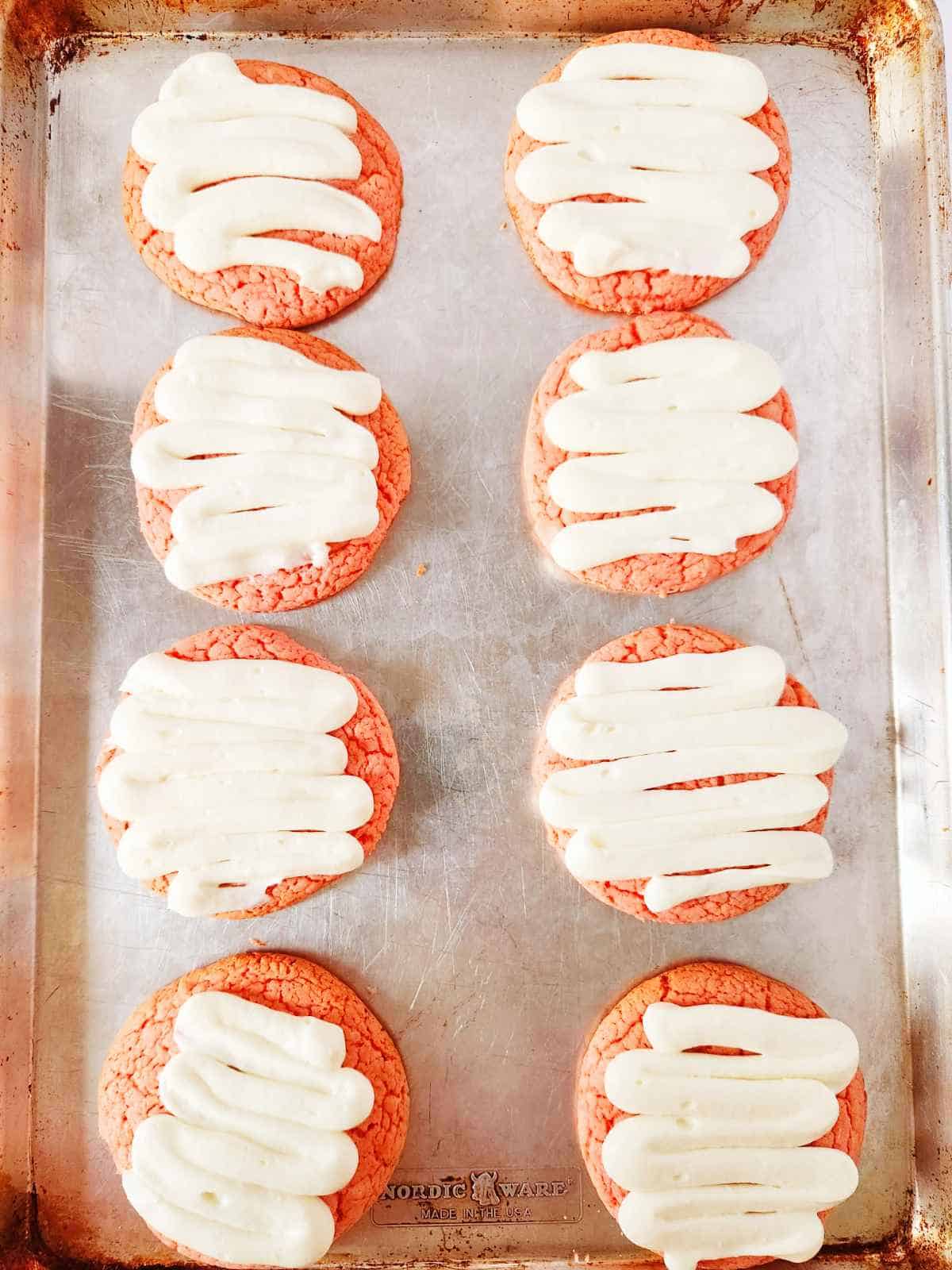 buttercream frosting piped on strawberry cookies.